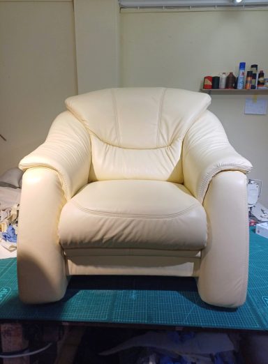 Beige Ledersessel mit breiten Armlehnen und weich gepolstertem Sitz.