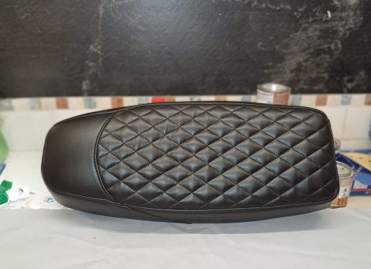 Schwarzer, genähter Sitzbezug mit diagonalen Rautenmustern.