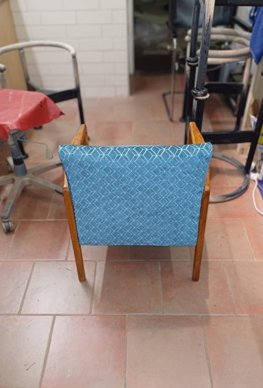 Blauer gepolsterter Stuhl mit Holzrahmen, von hinten betrachtet.